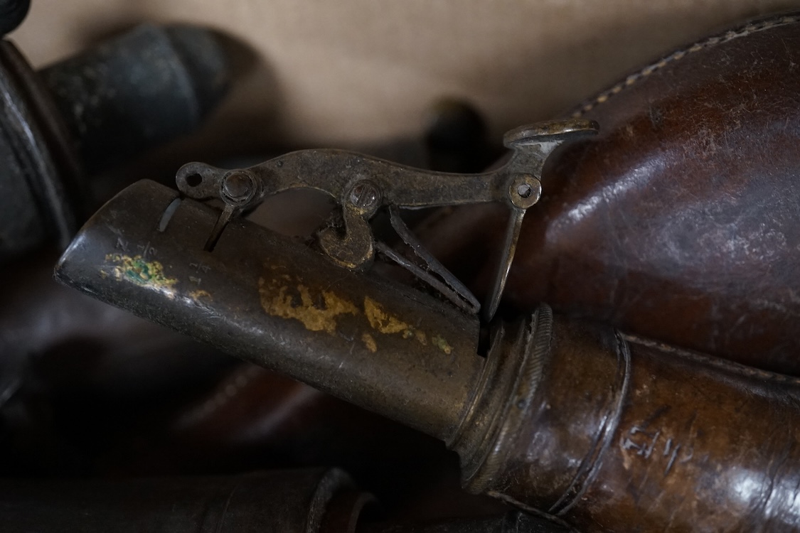 Three gun-sized copper powder flasks, two of which are embossed, together with four leather shot bags each with sprung chargers, two iron and two brass examples, one of which is embossed with a hunting scene (7)